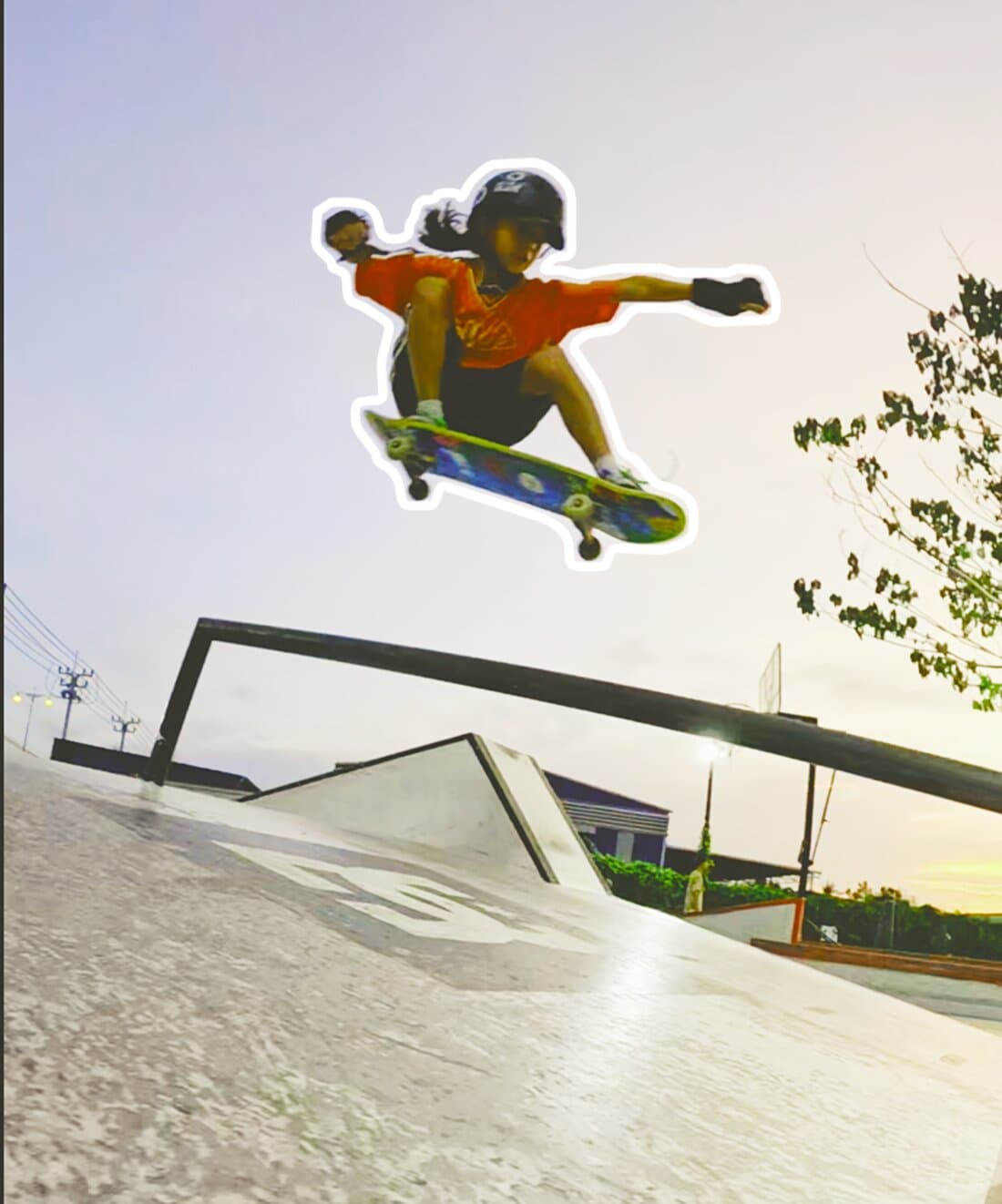 Young skater mid-air over a skatepark ramp at dusk
