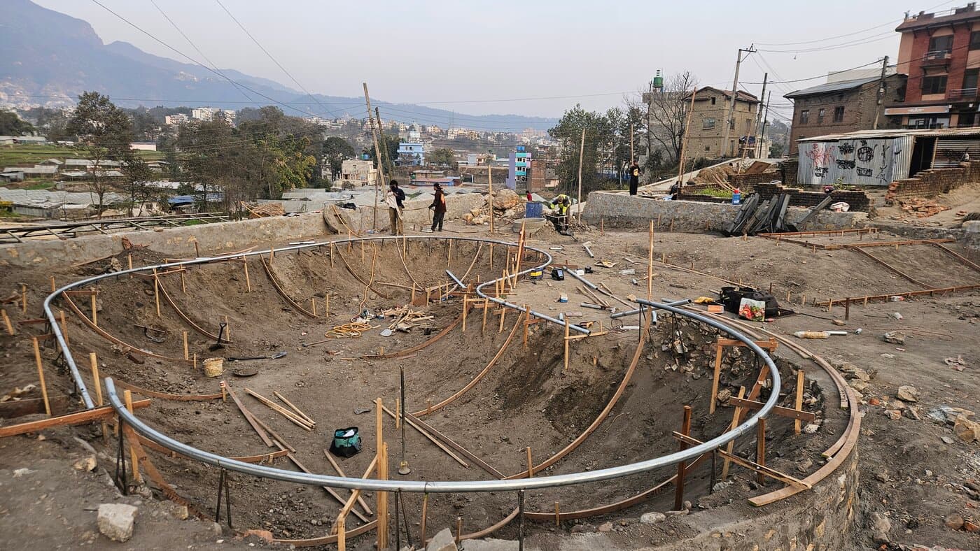 Skatepark construction site with curved formwork near a town