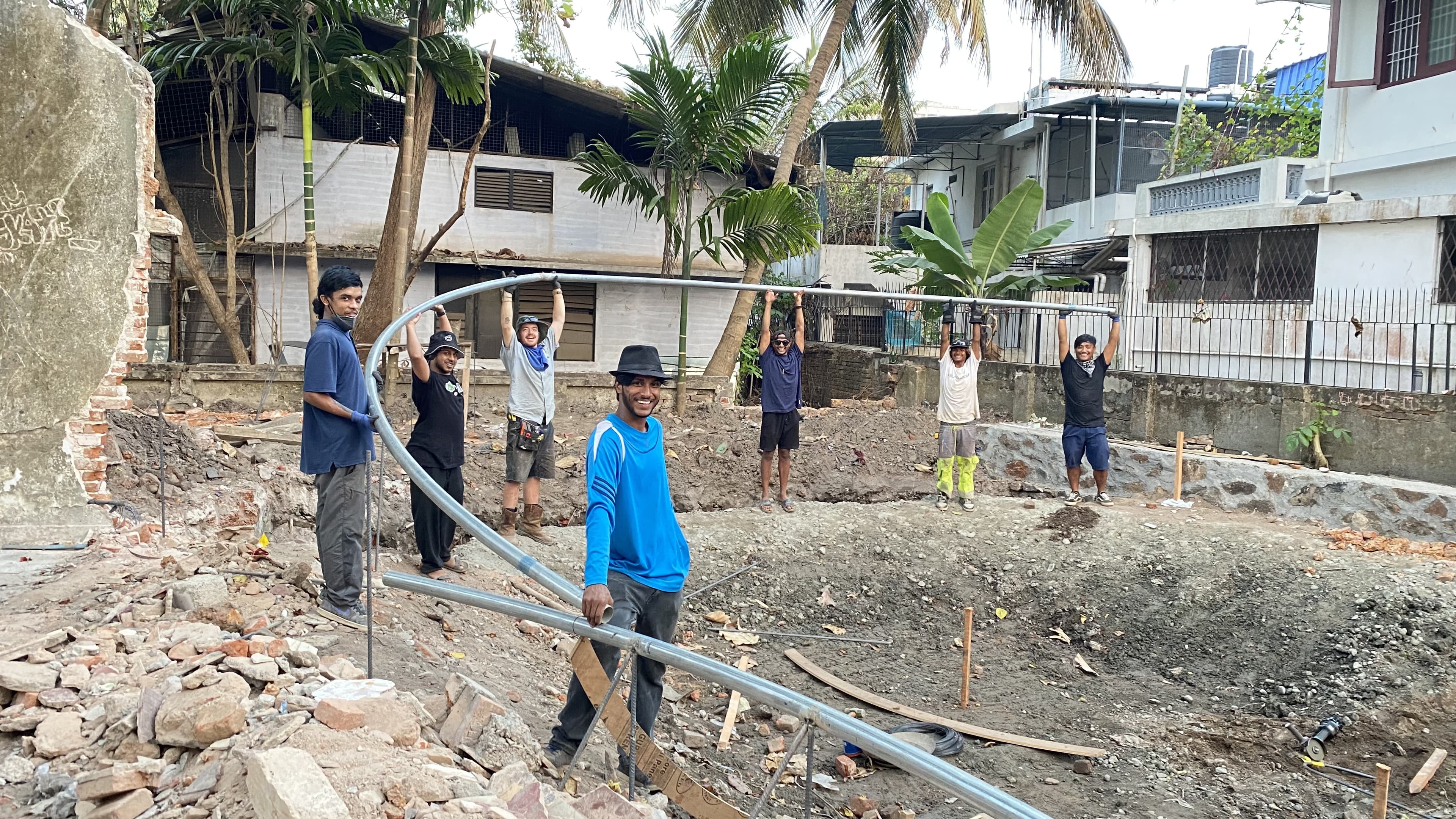 Skatepark construction crew lifting a steel rail into place on site